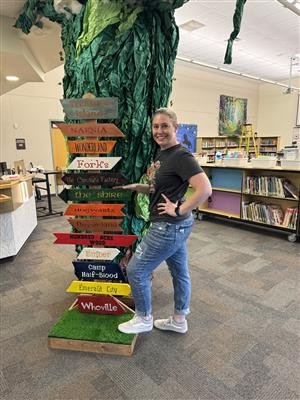 Mrs. Moser standing next to a sign post