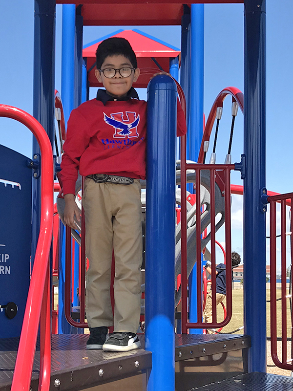 boy in uniform-red Hawthorne Hawks sweatshirt and tan long pants 