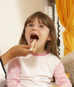 Doctor with stick checking little girl's throat 